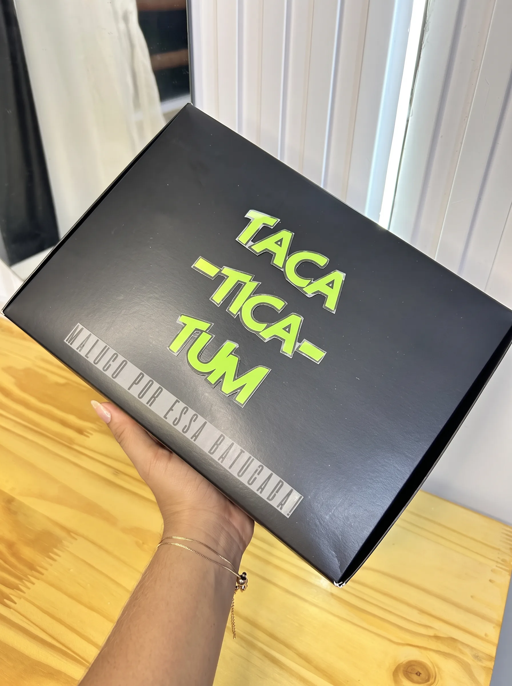 Caixa preta TACATICATUM com letras verdes e a frase Maluco por essa batucada